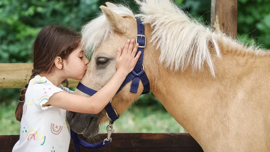 Jeune cavalière faisant un bisou à son poney