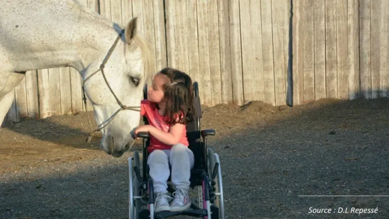 Petite fille en fauteuil à côté d'un cheval 